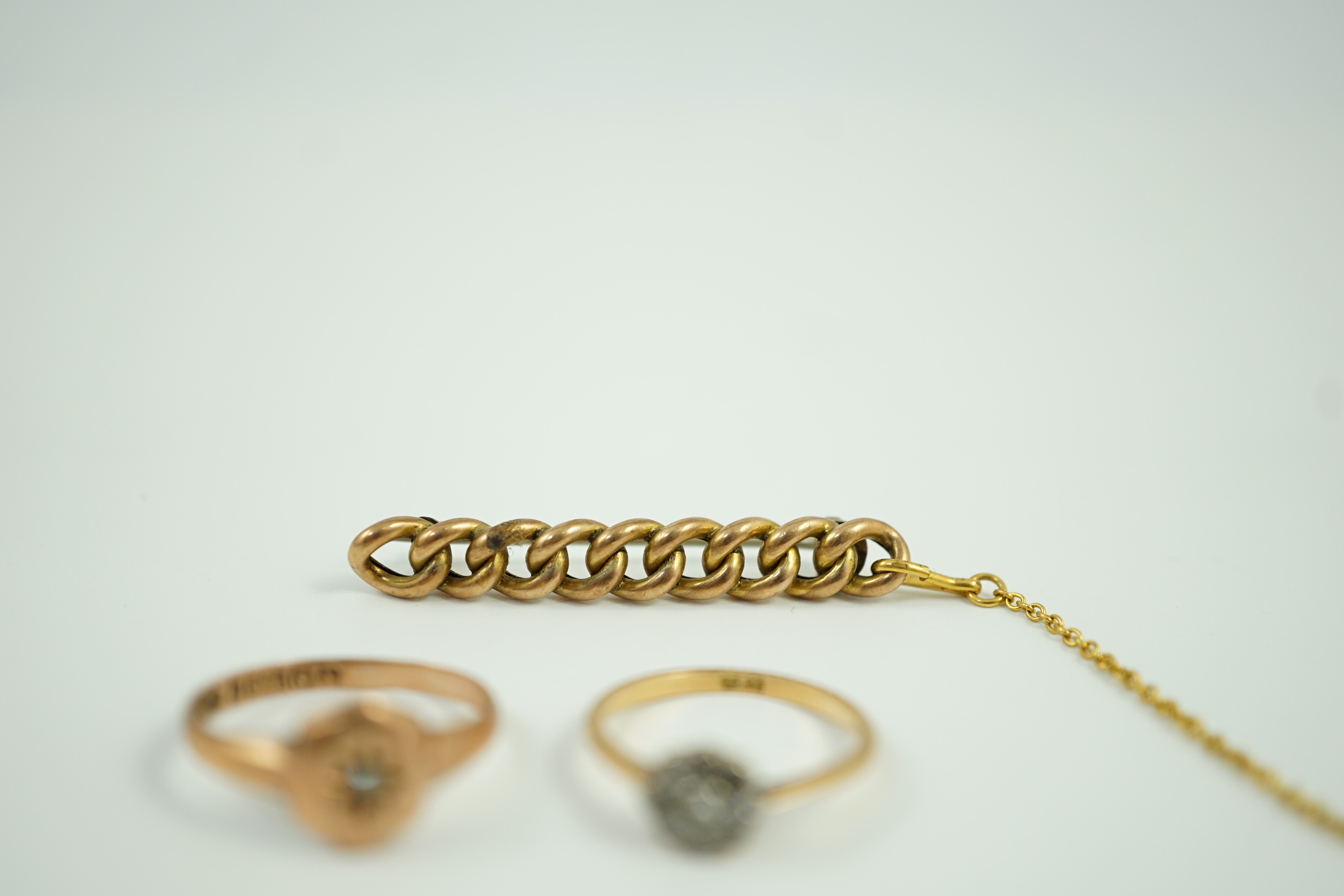 A small 18ct and diamond set cluster ring, size K, gross 1.2 grams, a 9ct gold and diamond chip set ring and a yellow metal curb link bar brooch, gross 5.1 grams.